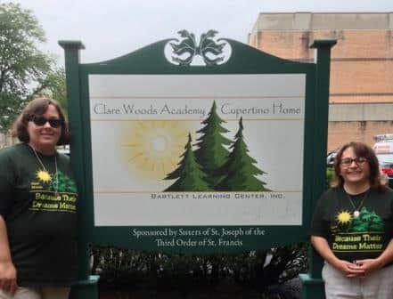 two-women-green-shirts-sign