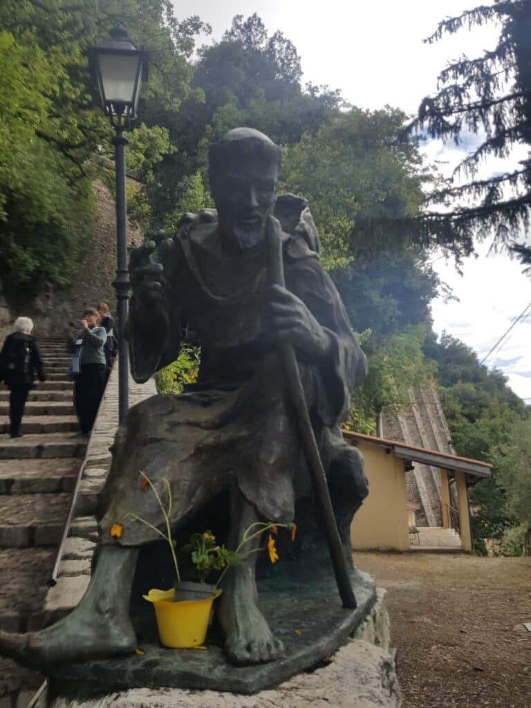 statue-man-robe-staff-stone-steps-lampost-yellow- pot-flowers