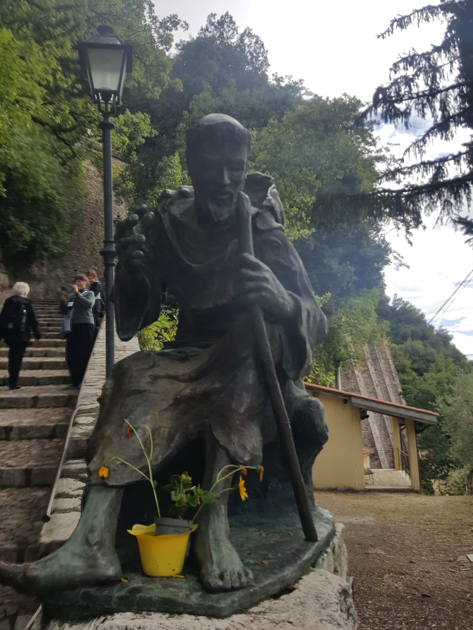 statue-man-robe-staff-stone-steps-lam post-yellow- pot-flowers