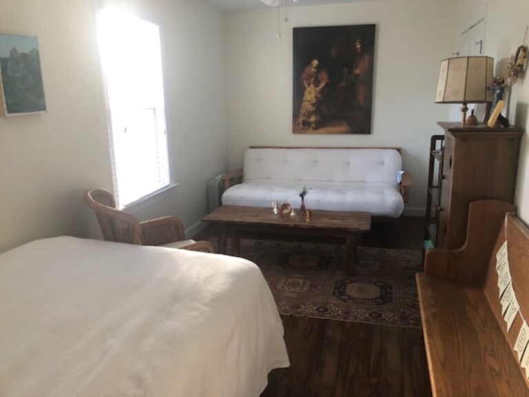 bedroom with bed, wooden bench, futon, window and painting