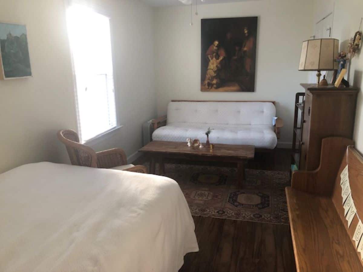 bedroom with bed, wooden bench, futon, window and painting