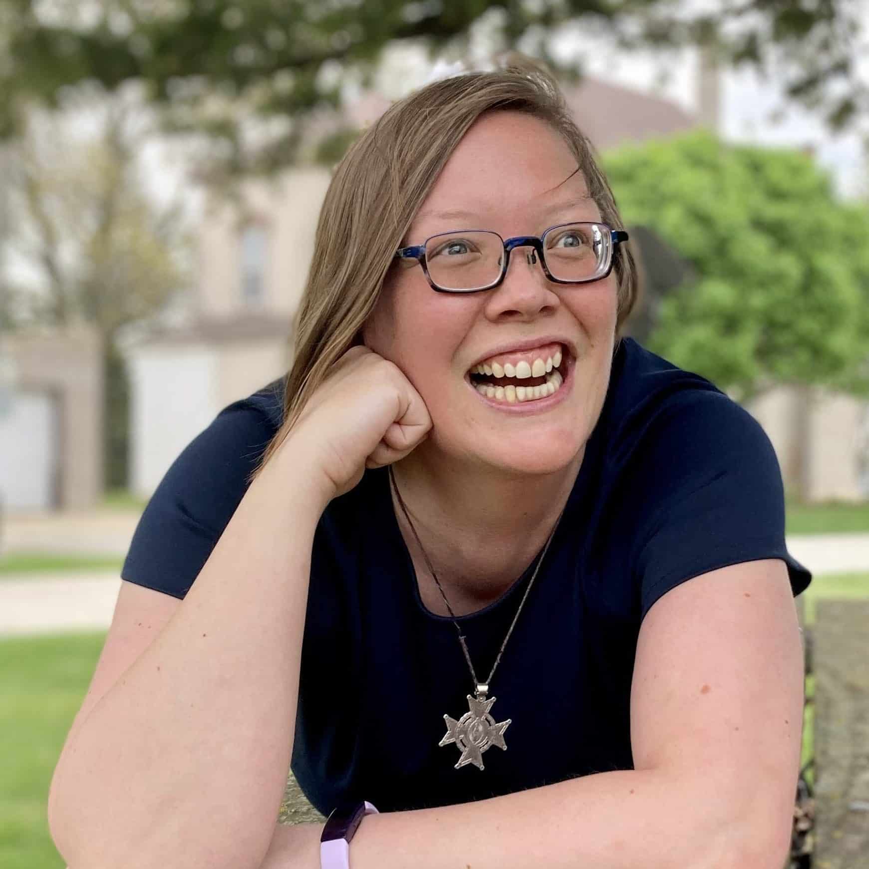 Sister Julia FSPA on a picnic table, head leaning on hand, laughing