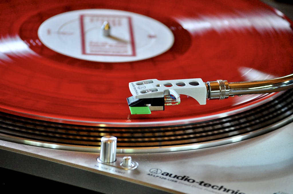 A detailed shot of a classic turntable playing a vibrant red vinyl record, showcasing a retro vibe.