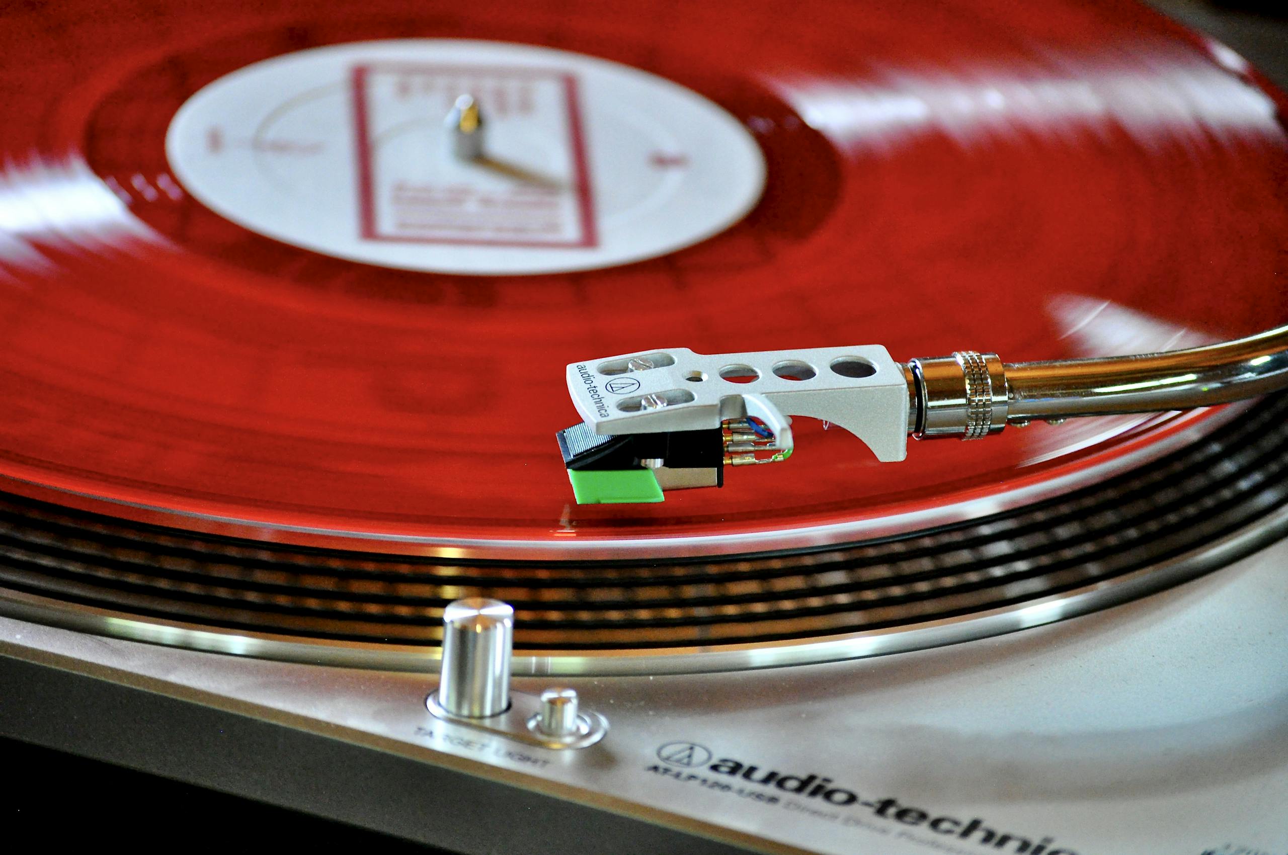 A detailed shot of a classic turntable playing a vibrant red vinyl record, showcasing a retro vibe.