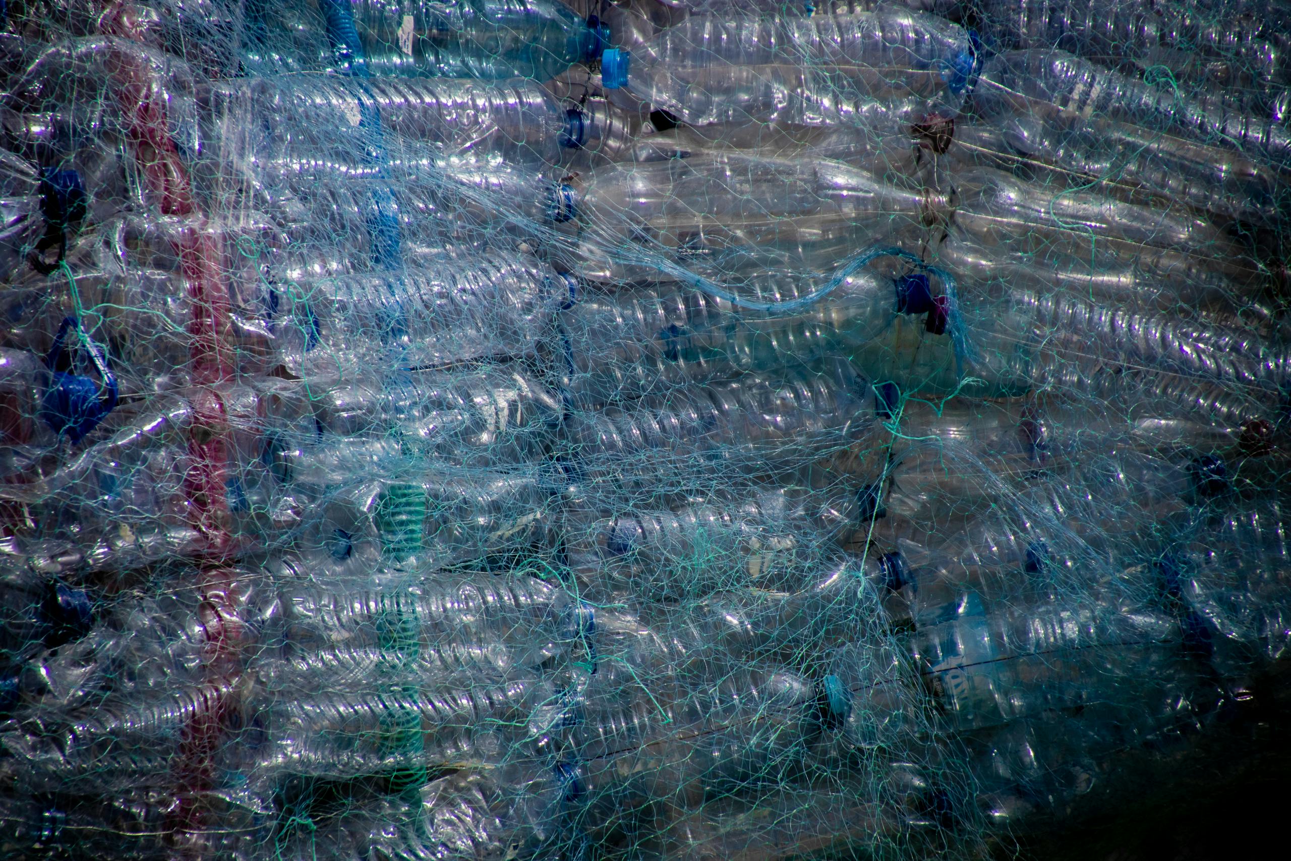 Plastic bottles tightly wrapped in netting for recycling, highlighting waste management.